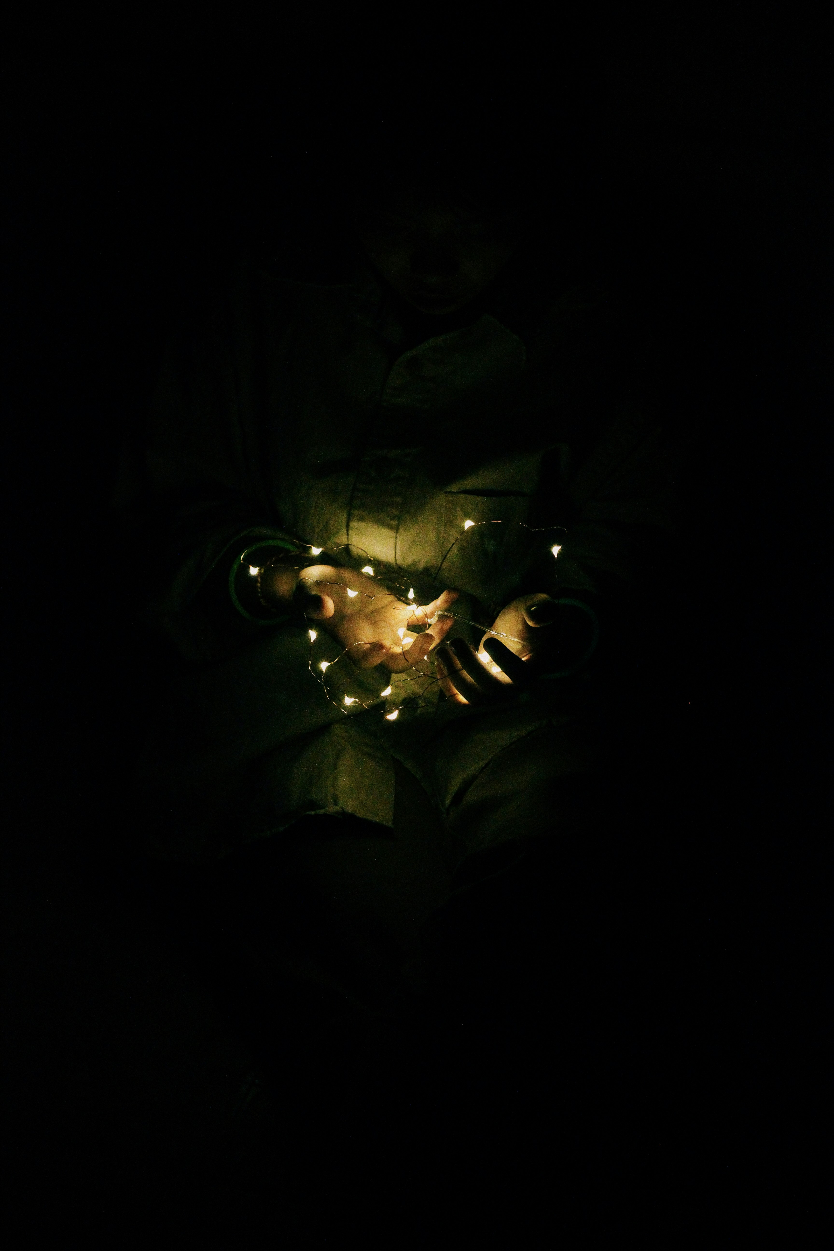 woman holding string light in dimmed room